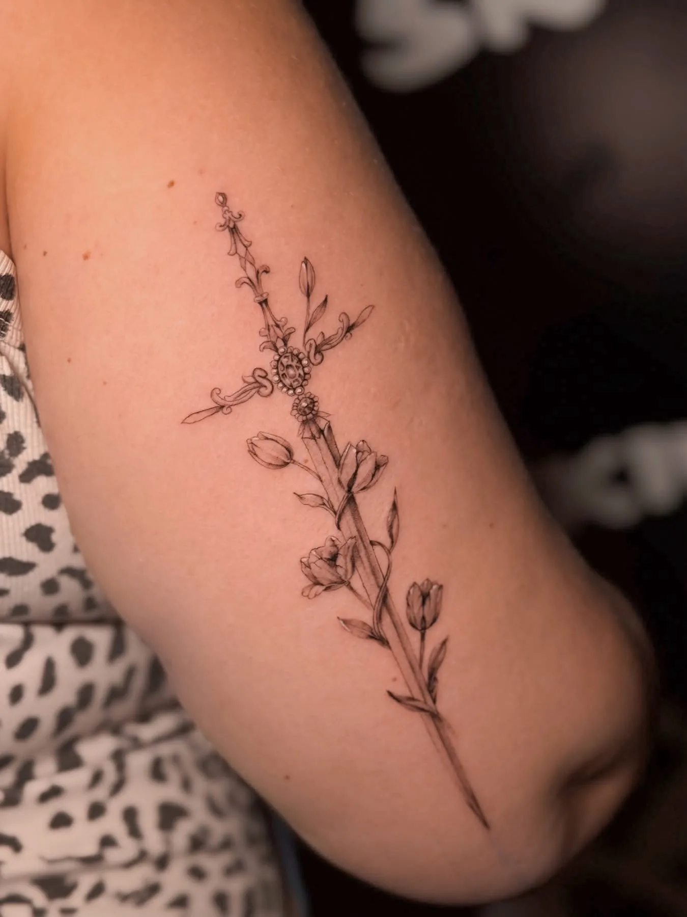 Filigranes Blumen-Tattoo auf der Rückseite des Oberarms