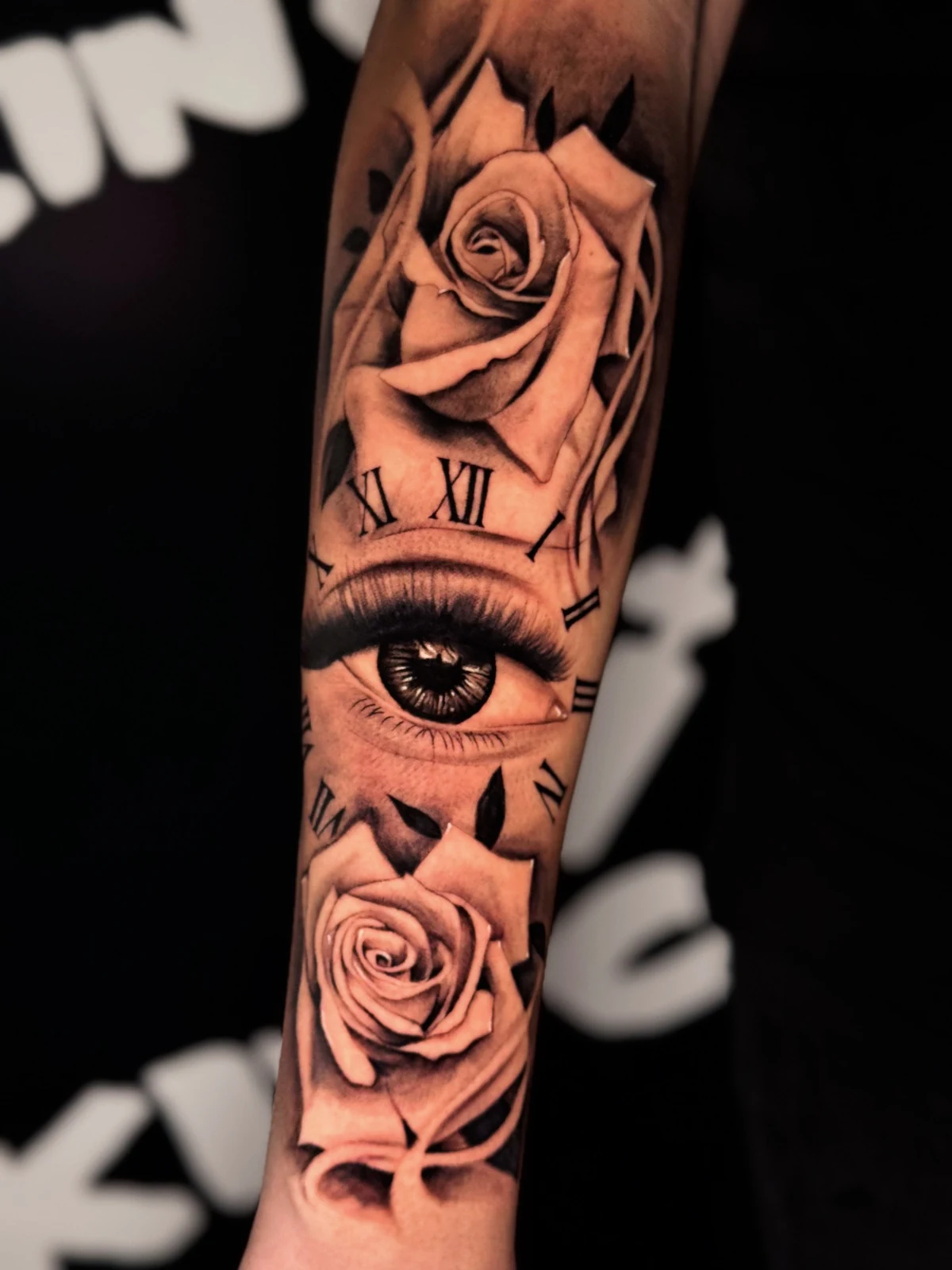 Realistisches Black-and-Grey-Tattoo mit Rosen, Auge und römischen Ziffern am Unterarm – Arbeit von Merci, Skin City Tattoo.